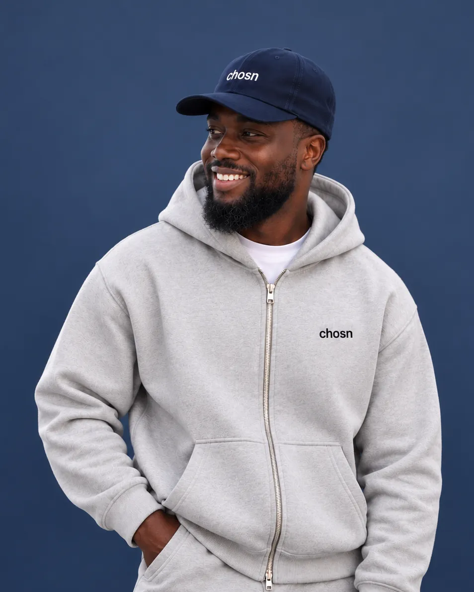 The chosn model in the navy Everyday Signature Cap and an ash Studio Zip Hoodie